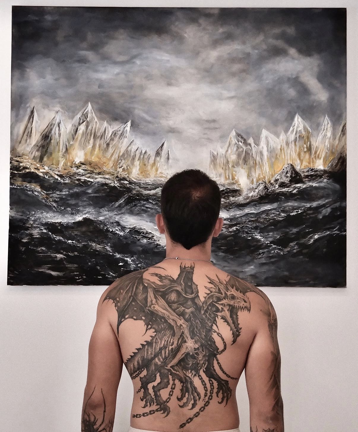 Dragon back-piece tattoo with a storm and mountain composition